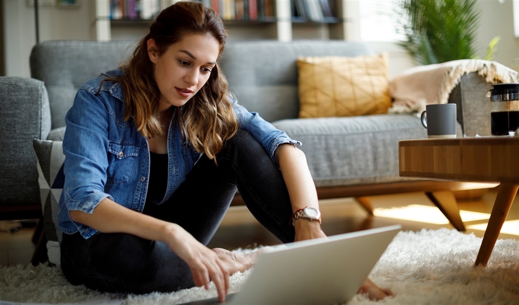 Millennial woman looking up budgeting tools on laptop in home
