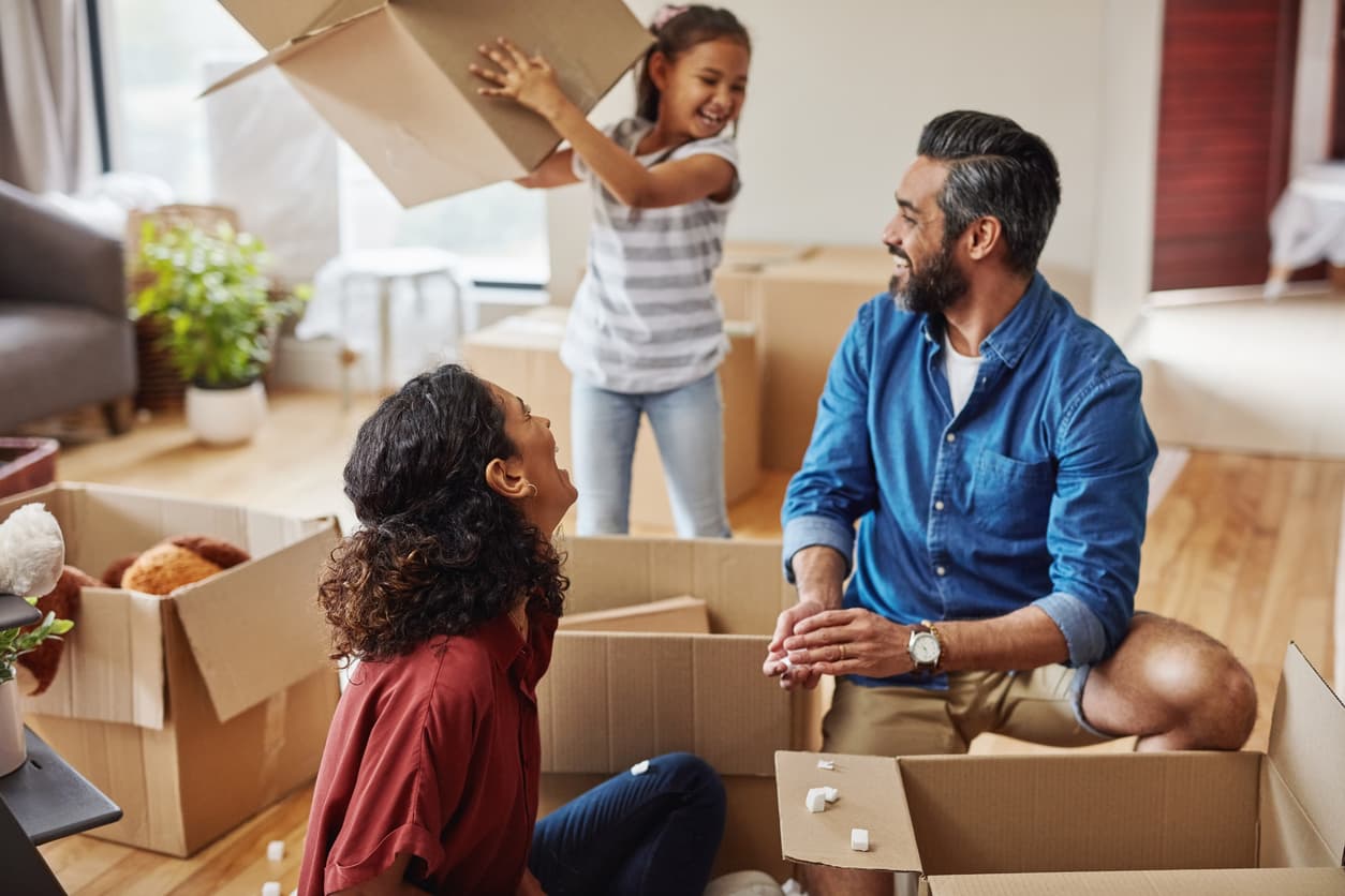 Family of three unpack boxes in their new home joyfully