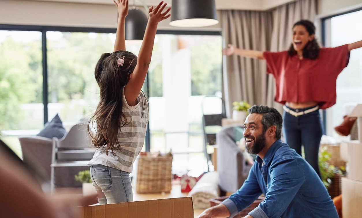 Family of three unpack boxes in their new home joyfully