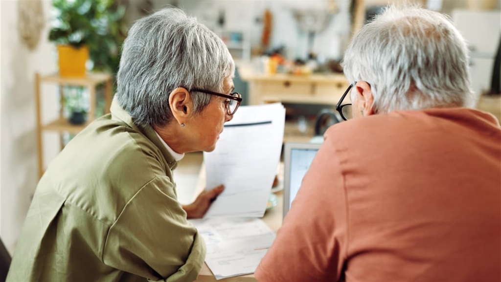 Older couple looking over financial statements at kitchen table