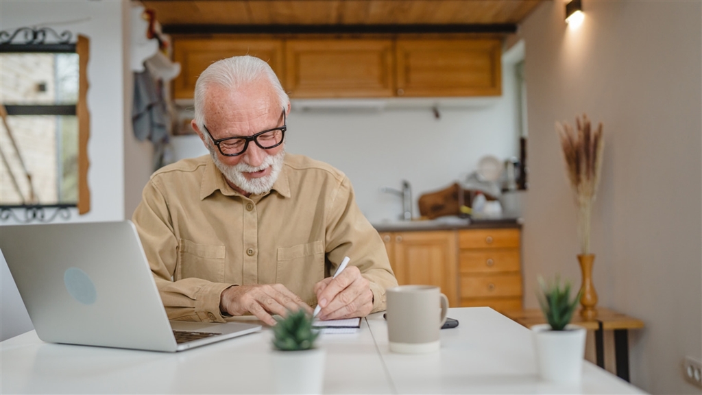 Older gentleman at home office writing a check