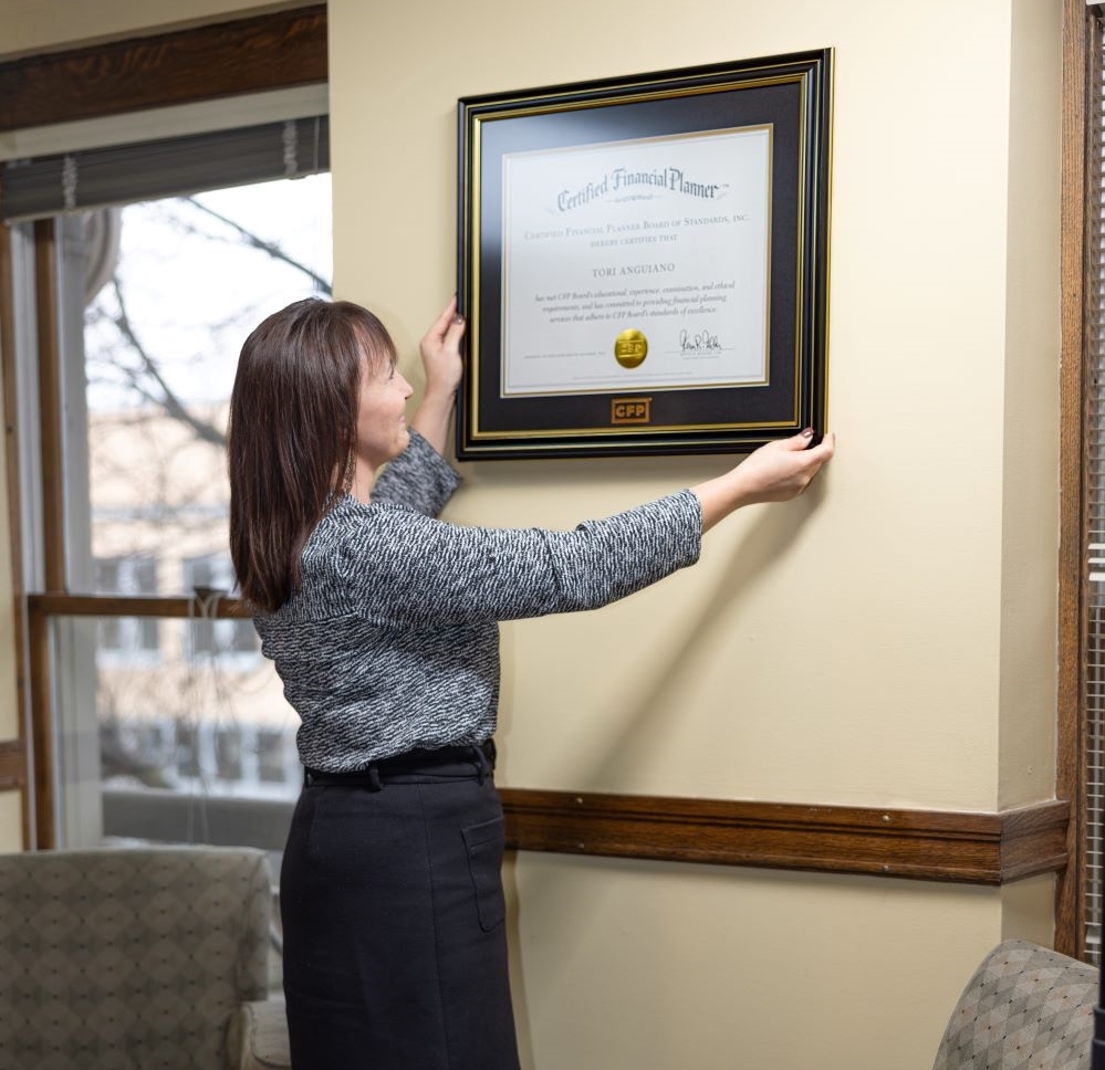 Tori Anguiano hanging certificate on wall