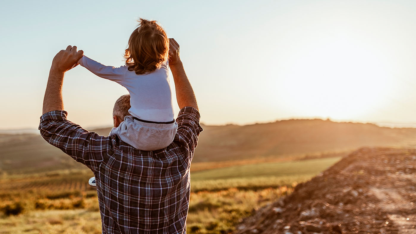 father and young daughter walking on shoulders outside